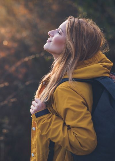Una mujer en un bosque con su abrigo y mochila
